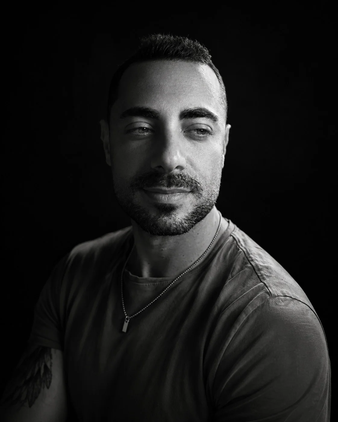 Portrait en noir et blanc de Jeremy Celeste, photographe mariage, regardant sur le côté avec un sourire discret
