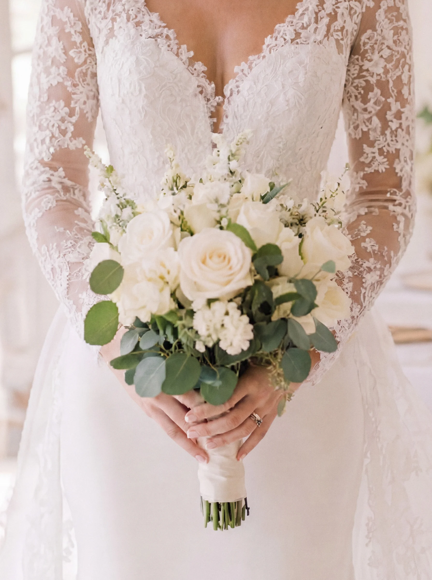 Mains de la mariée tenant un bouquet de roses blanches et feuillage vert, lors d'un mariage à Valence