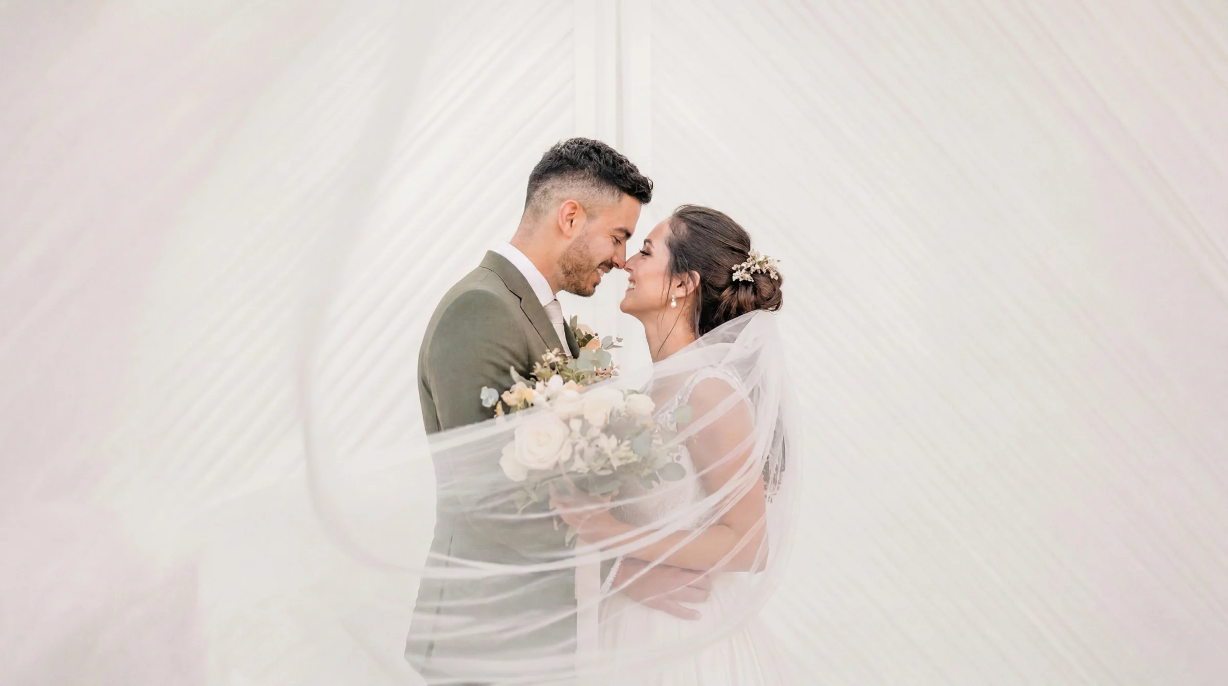 Jeunes mariés souriants sous un voile aérien, reportage mariage à Valence, ambiance lumineuse et romantique