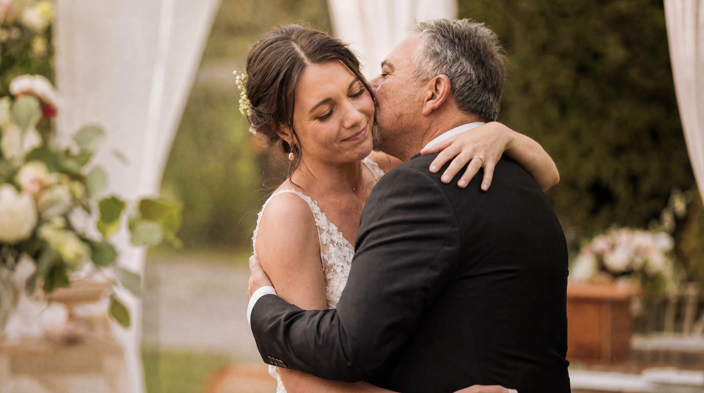 Mariée émue dans les bras de son père lors d'un reportage mariage à Montélimar, ambiance tendre et lumineuse