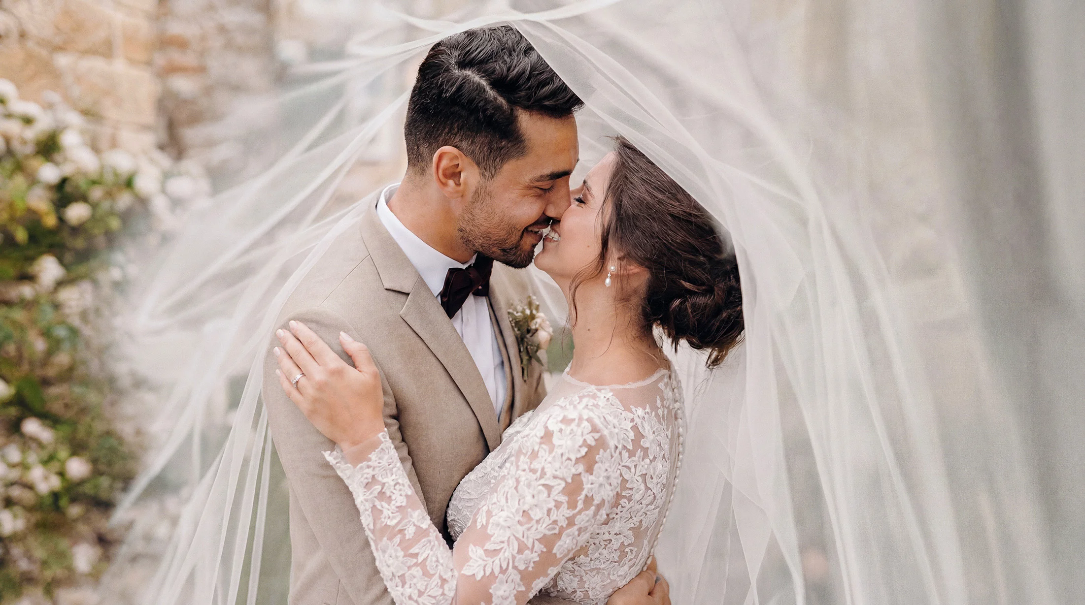 Jeunes mariés s'embrassant sous un voile, un reportage de mariage à Romans tout en tendresse et complicité