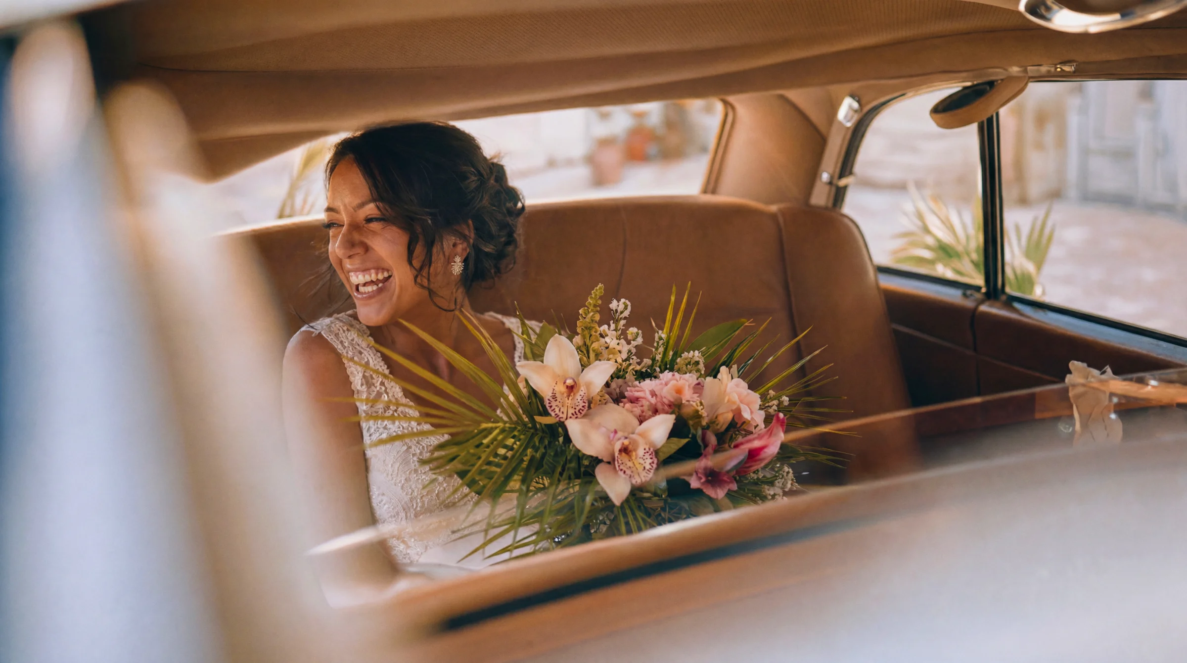 Mariée radieuse riant dans une voiture vintage avec son bouquet, reportage mariage à Portes-lès-Valence